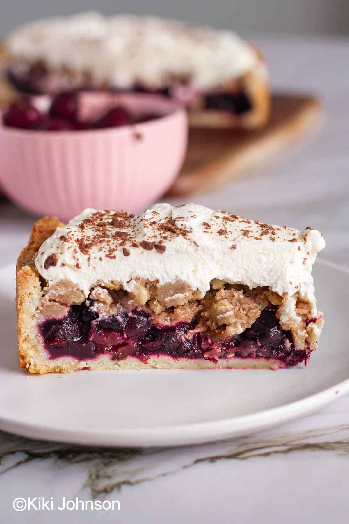 a slice of German Sour Cherry Cake with Streusel topping and whipped cream 