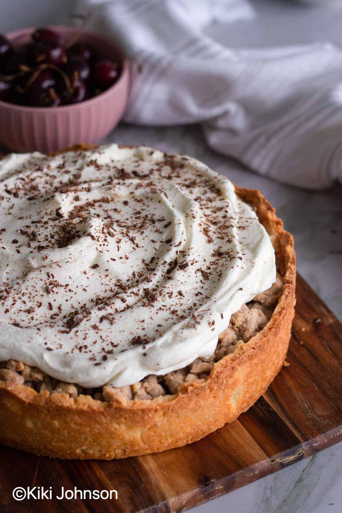 a traditional German sour cherry cake with streusel topped with whipped cream and shaved dark chocolate