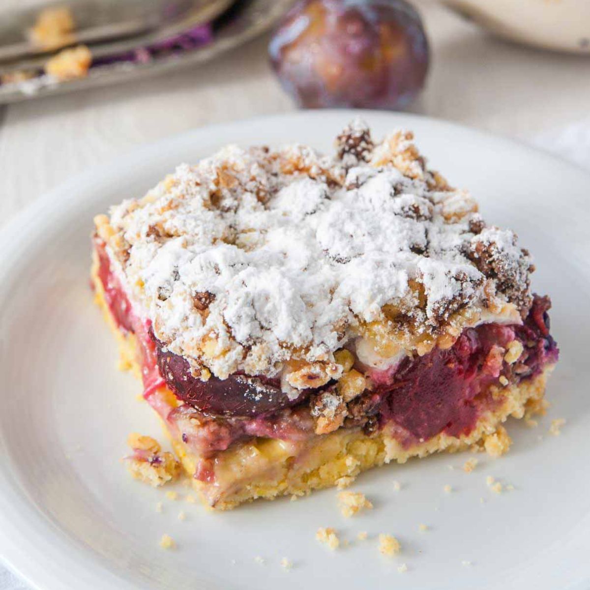 plum coffee cake with streusel topping on a cake plate