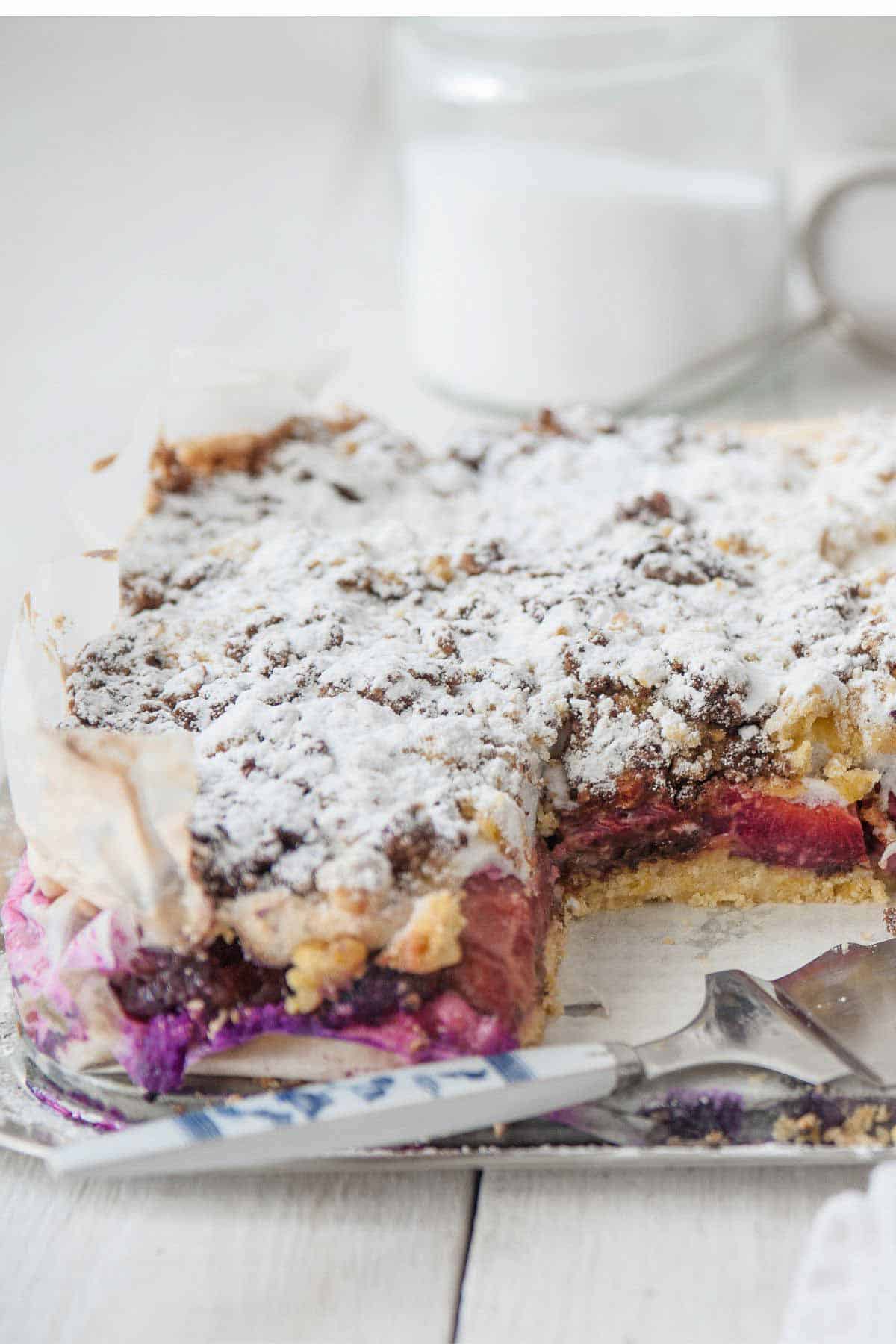 angeschnittener Zwetschgen Kuchen vom Blech mit Baiser und Mohn Nuss Streuseln bedeckt