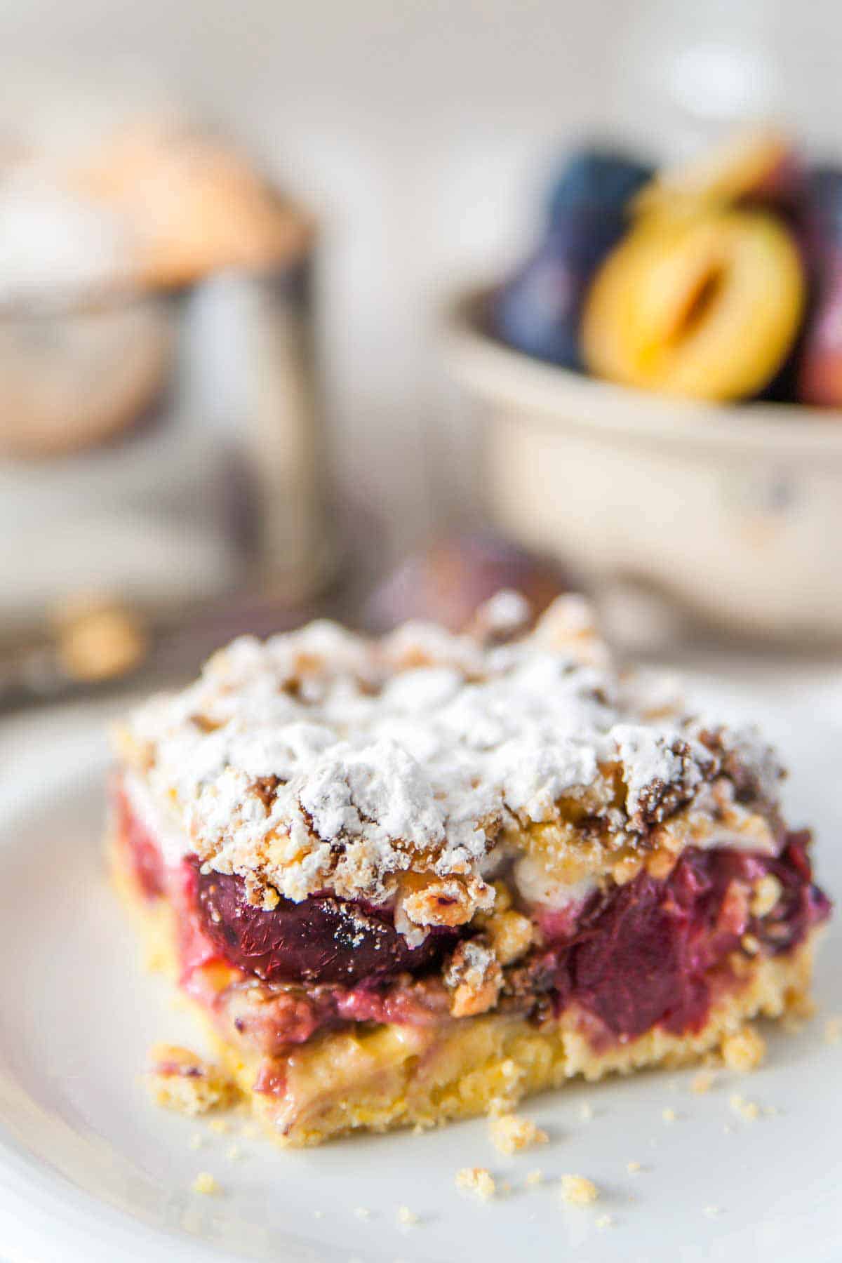 ein Stück Zwetschgen Kuchen mit Mürbeteig vom Blech mit Baiser und Streuseln auf einem Kuchenteller