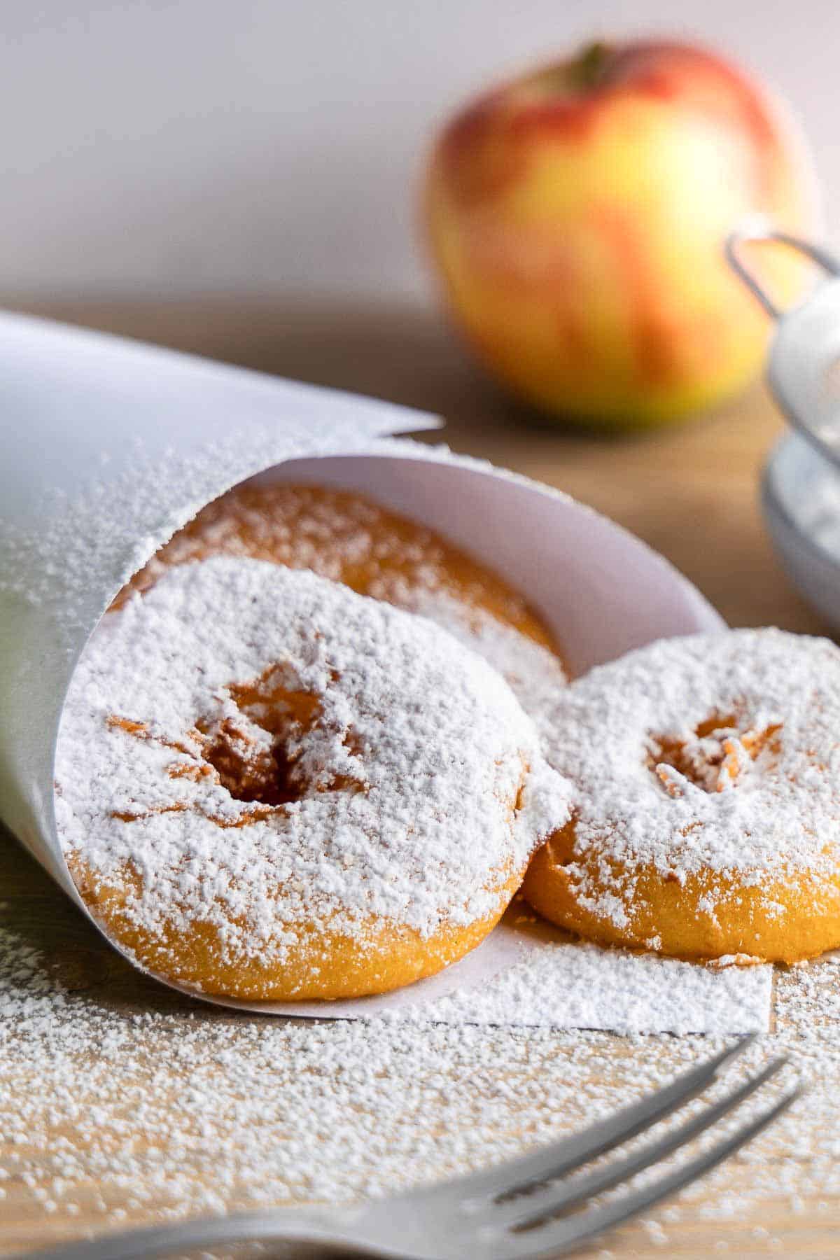 German Apple Fritters dusted with icing sugar in a paper bag 