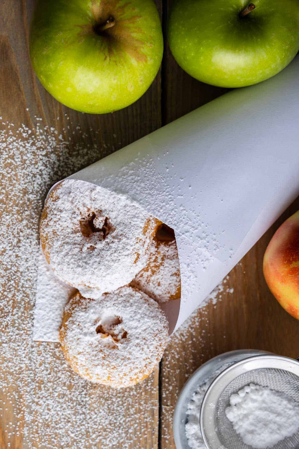 German apple fritters dusted with icing sugar in a paper bag 