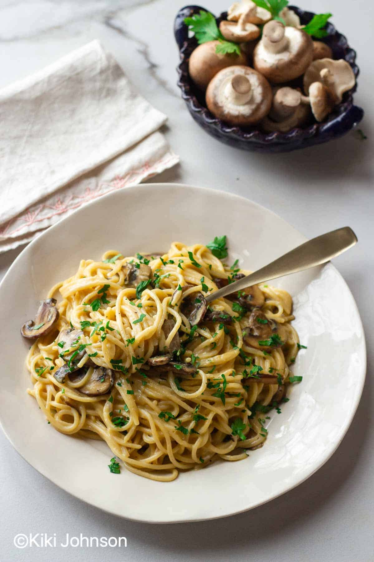 lactose free carbonara with mushrooms with a golden fork and shiitake mushrooms in the background