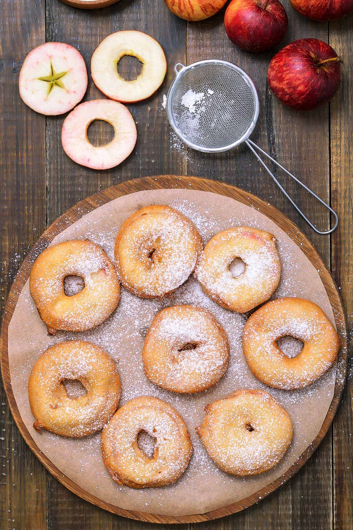 freshly fried beer battered apple rings dusted with icing sugar on a plate 