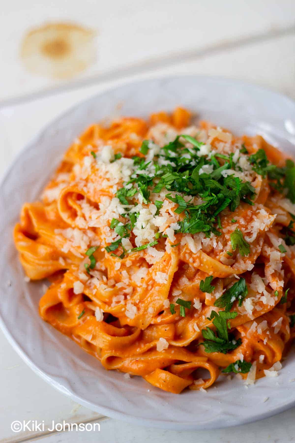 Paprika Nudeln auf einem weißen Teller mit Käse und Petersilie bestreut serviert 