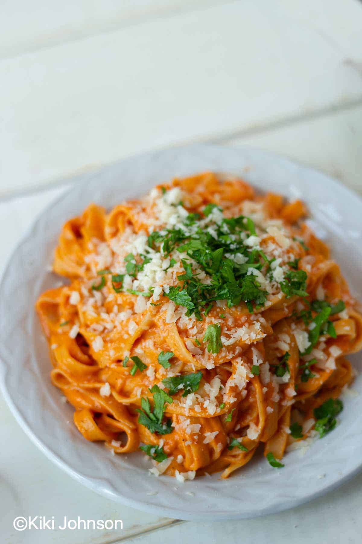 creamy paprika pasta with red bell pepper sauce topped with cheese and chopped basil 