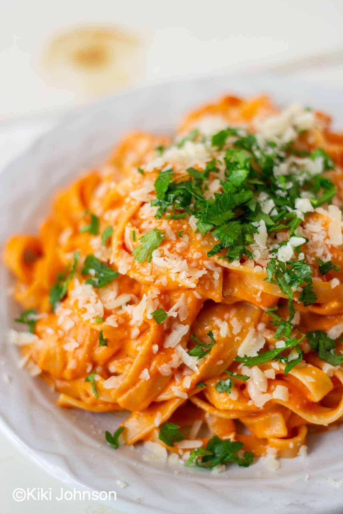 creamy paprika pasta with bell pepper sauce topped with cheese and parsley 