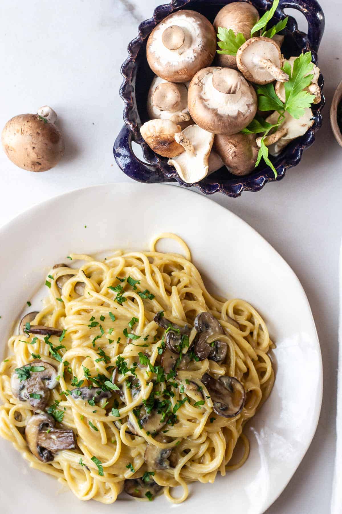 a plate of lactose free carbonara with mushrooms sprinkled with parsley