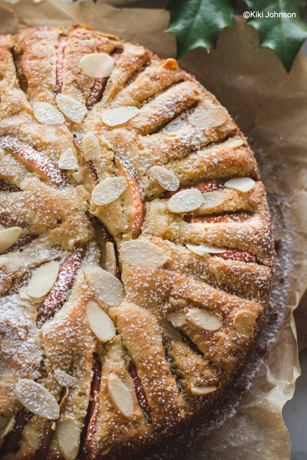 overhead shot of a German apple almond cake dusted with icing sugar and slivered almonds