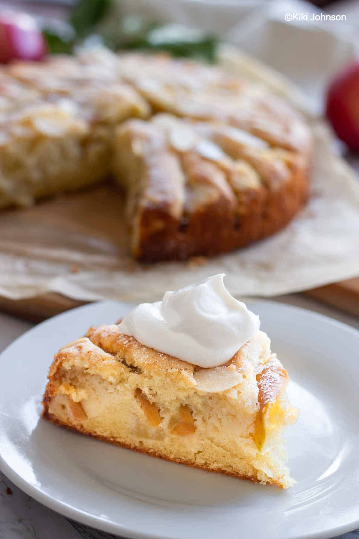 a slice of German Apple Almond Cake topped with a dollop of whipped cream