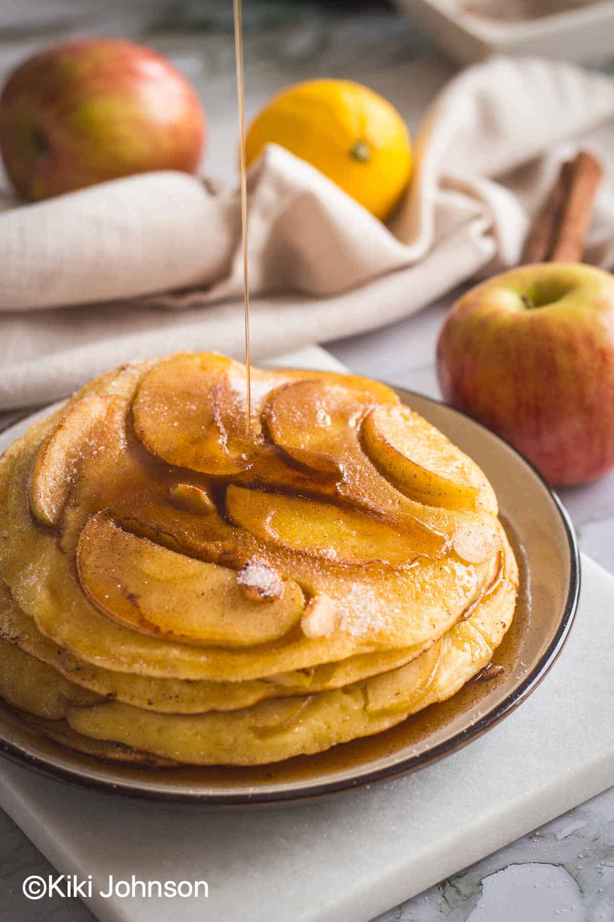 a stack of grannys German Apple Pancakes being drizzled with maple syrup