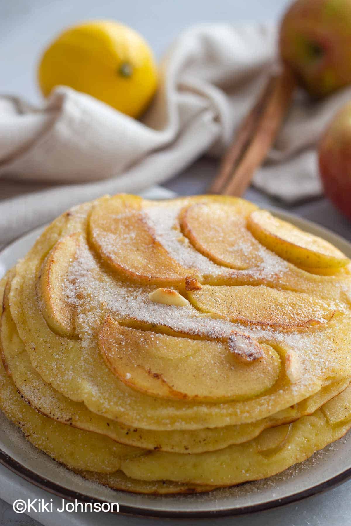 grannys German Apple Pancakes stacked on a plate dusted with cinnamon sugar