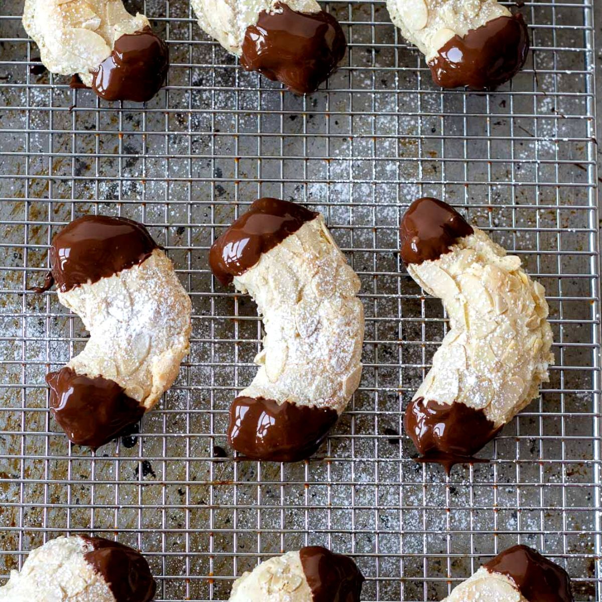 German Almond Horn Cookies dipped in dark chocolate on a cooling rack