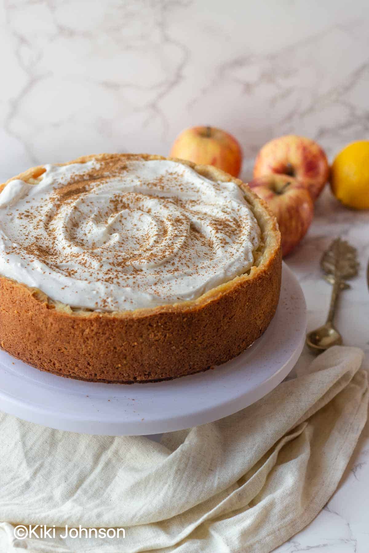 german apple cider cake with whipped cream topping on a cake plate