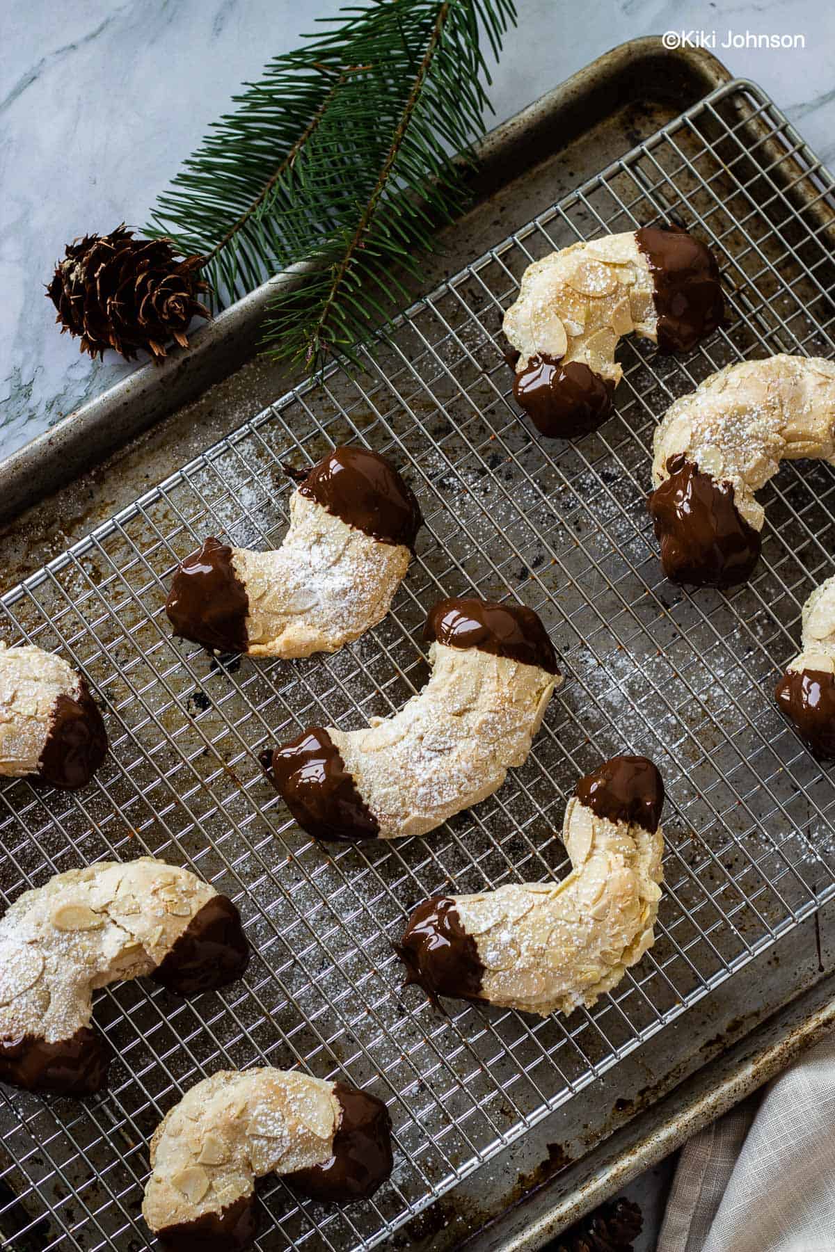 German Almond Horn Cookies dipped in melted chocolate on a cooling rack
