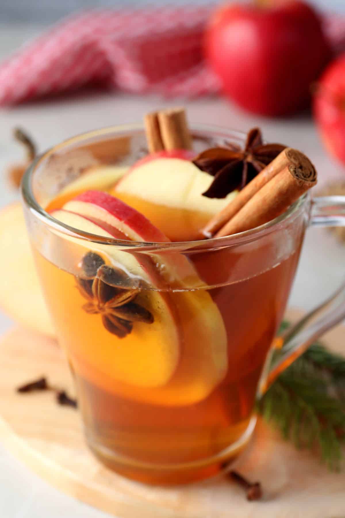 a glass with apple mulled white wine with apple slices, star anise and cinnamon sticks 