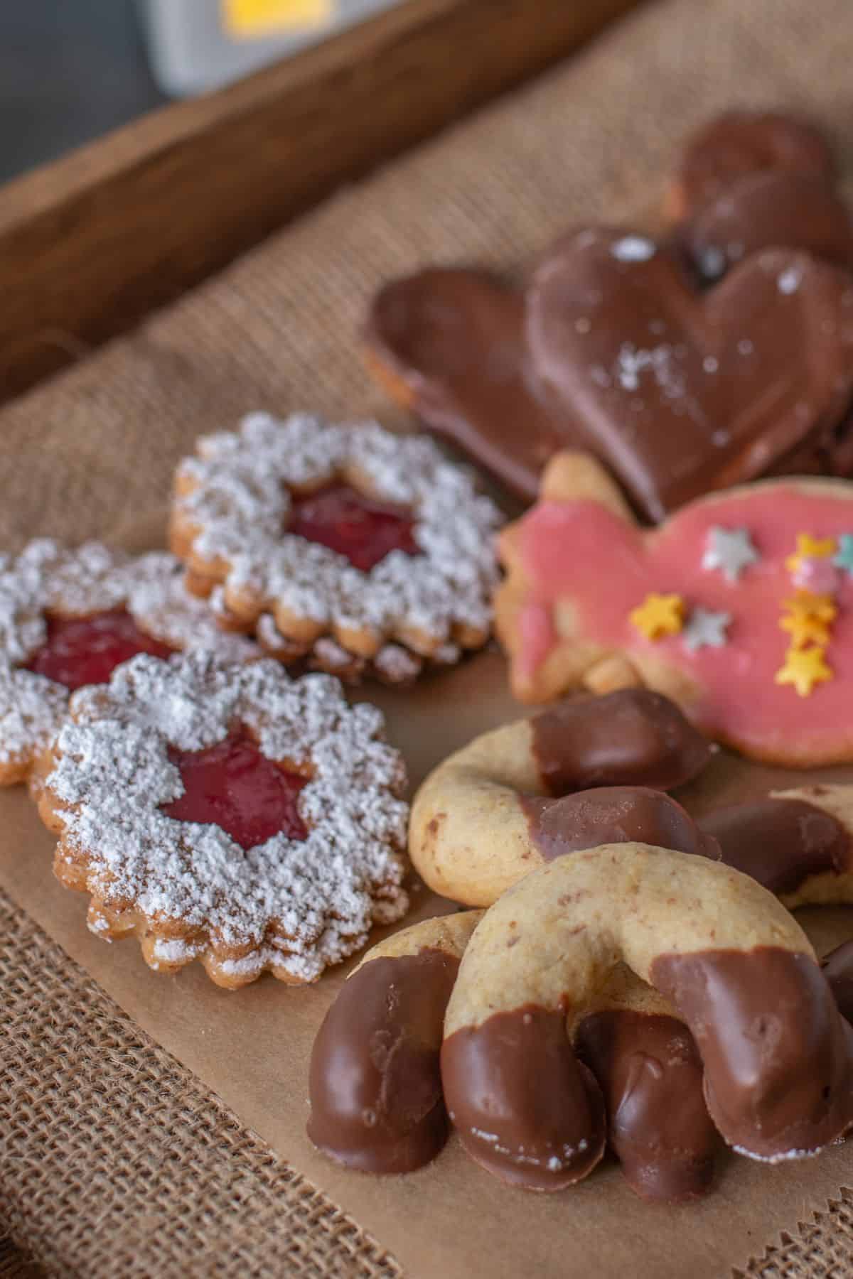 German christmas cookies like linzer and crescent cookies on a wooden tray
