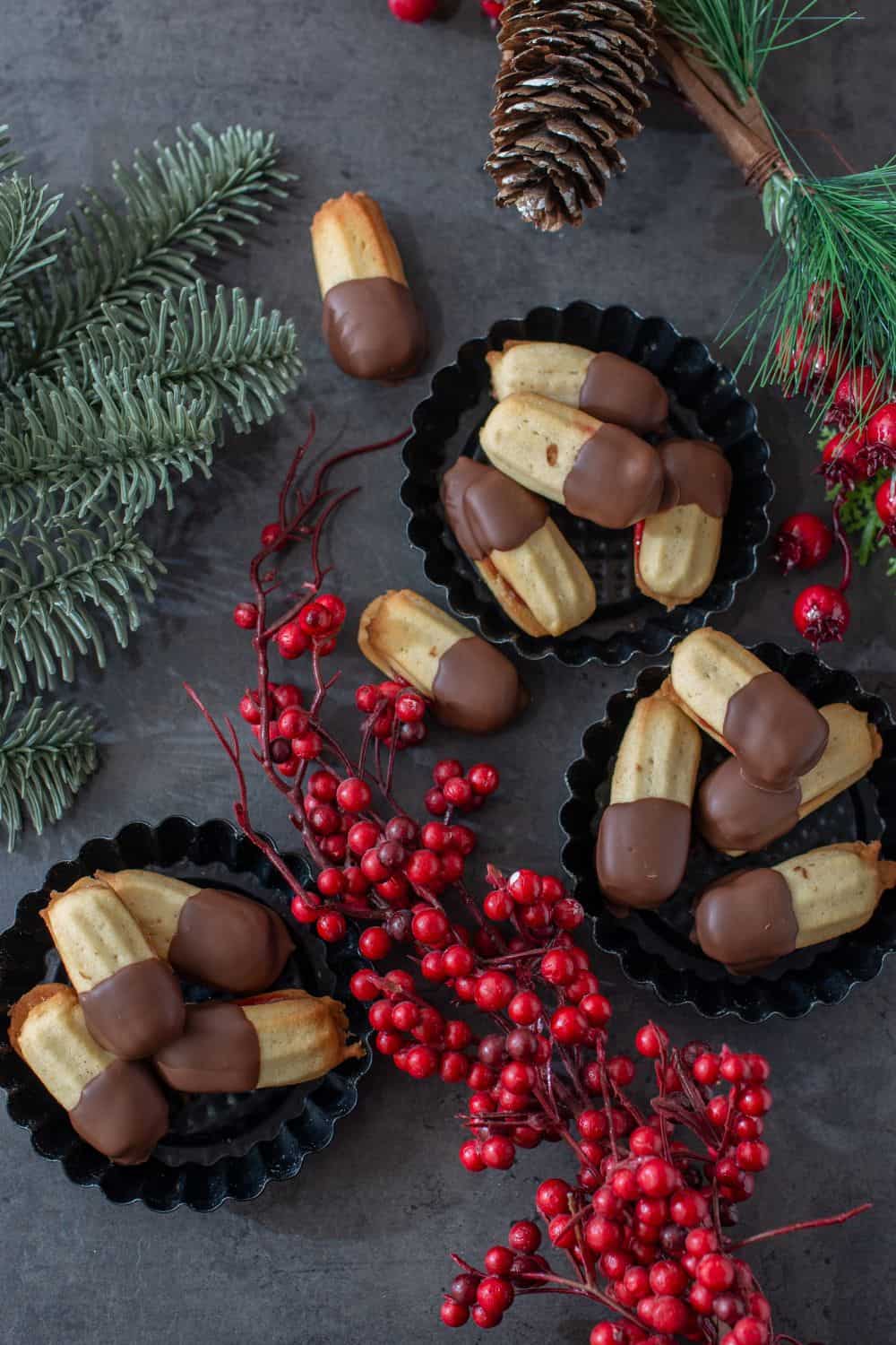 three small bowls with traditional Austrian Spritz Cookies with raspberry jam and dipped into melted chocolate