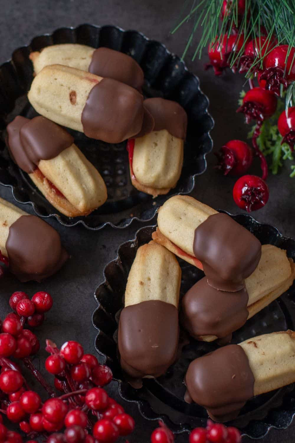 two small bowls with Austrian Spritz Cookies filled with jam and coated with chocolate