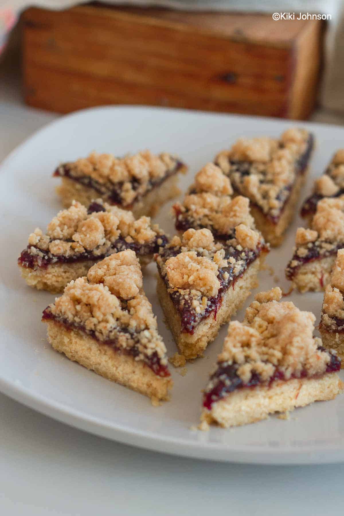 side view of traditional German cinnamon streusel plum jam cookies on a white plate 