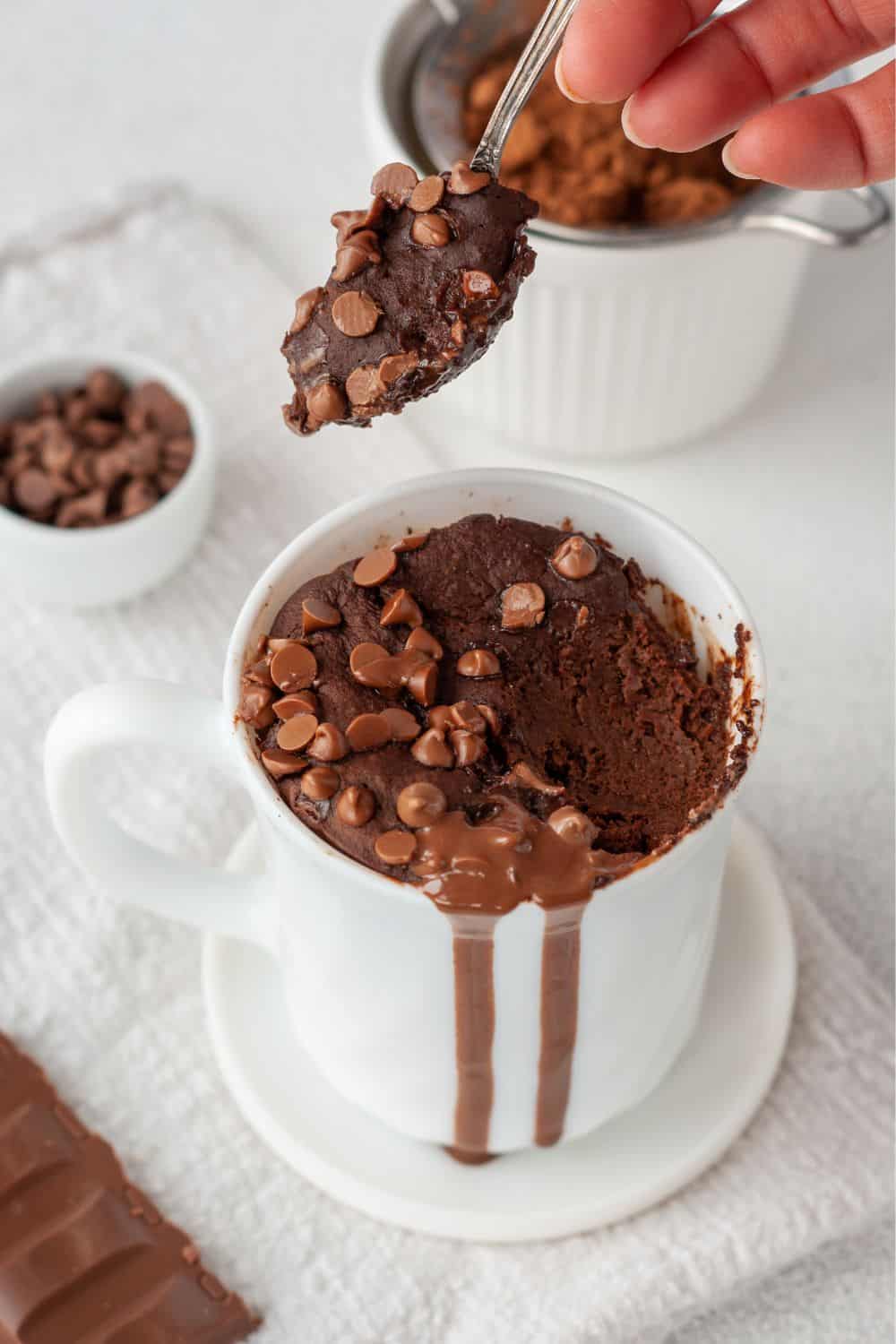 a half eaten chewy and fudgy vegan chocolate mug brownie in a white coffee mug