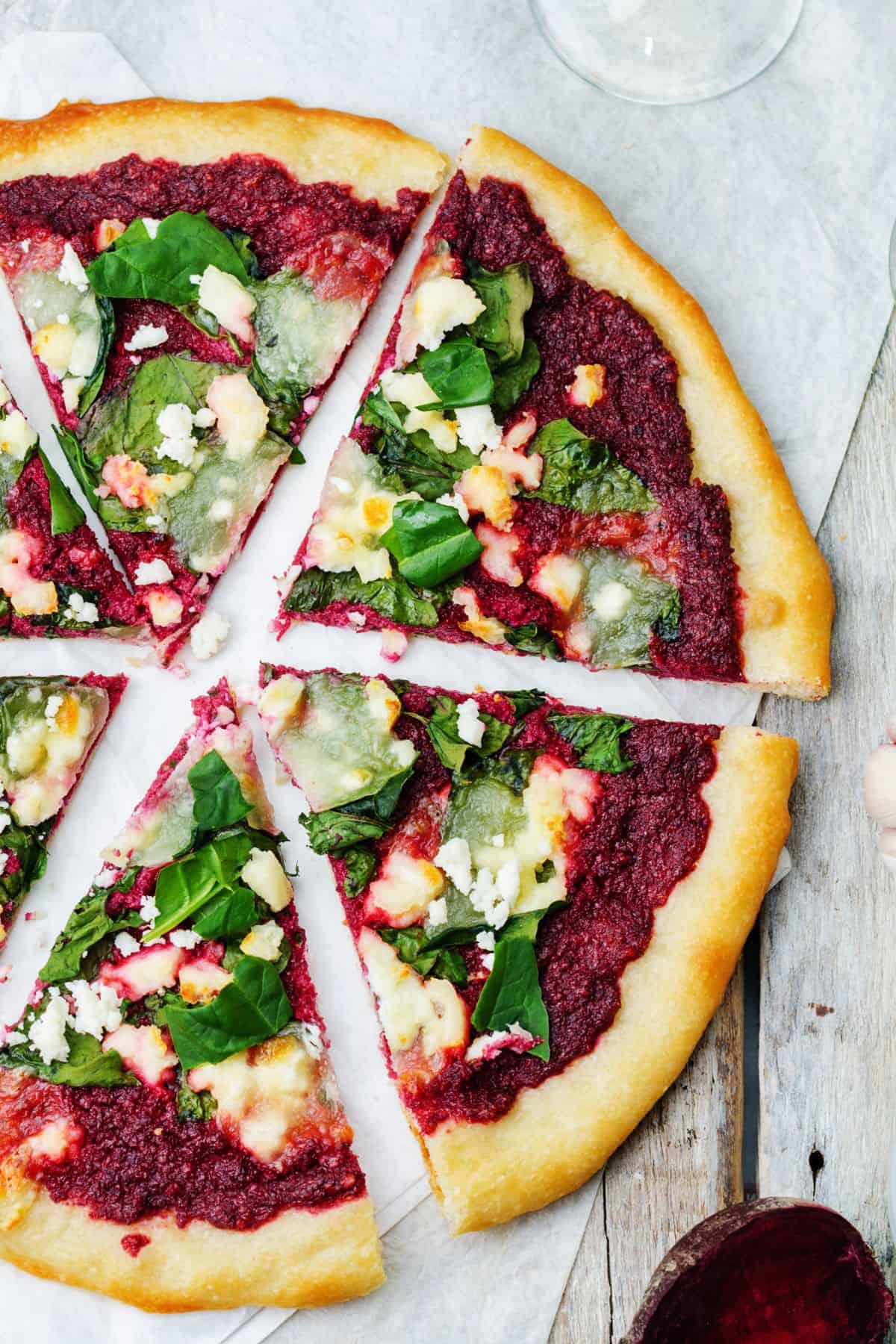 pizza topped with beetroot hummus, goat cheese and spinach