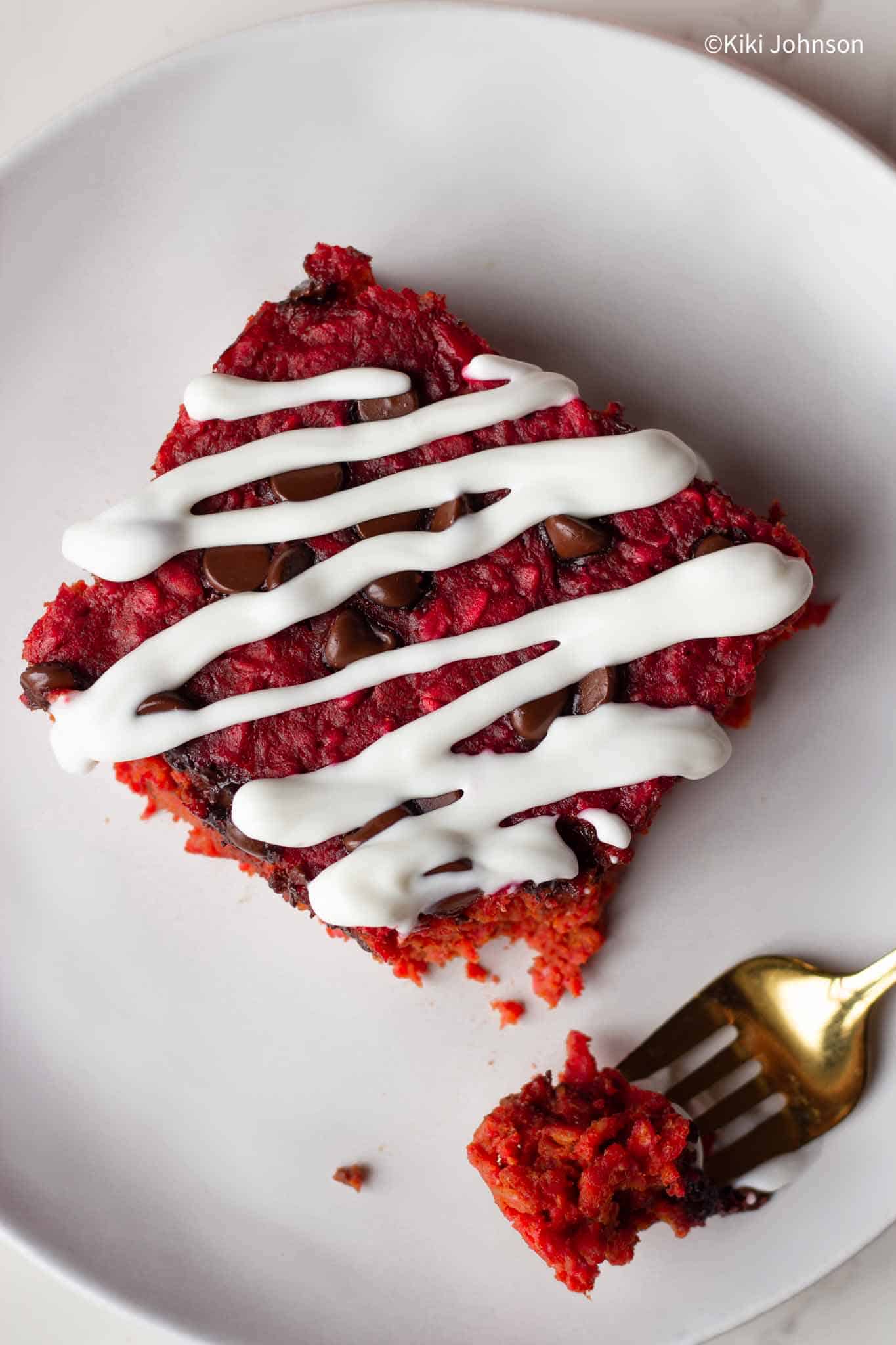 overhead shot of a slice of beet oatmeal bake on a plate drizzled with Greek yogurt topping 