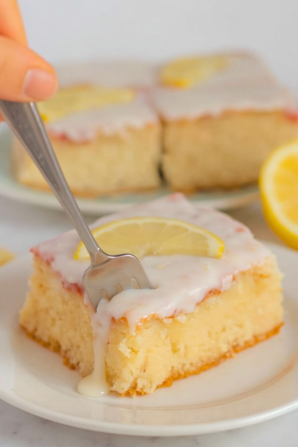 ein Stück eierlikör Blechkuchen mit Zitronenguss auf einem weissen Teller