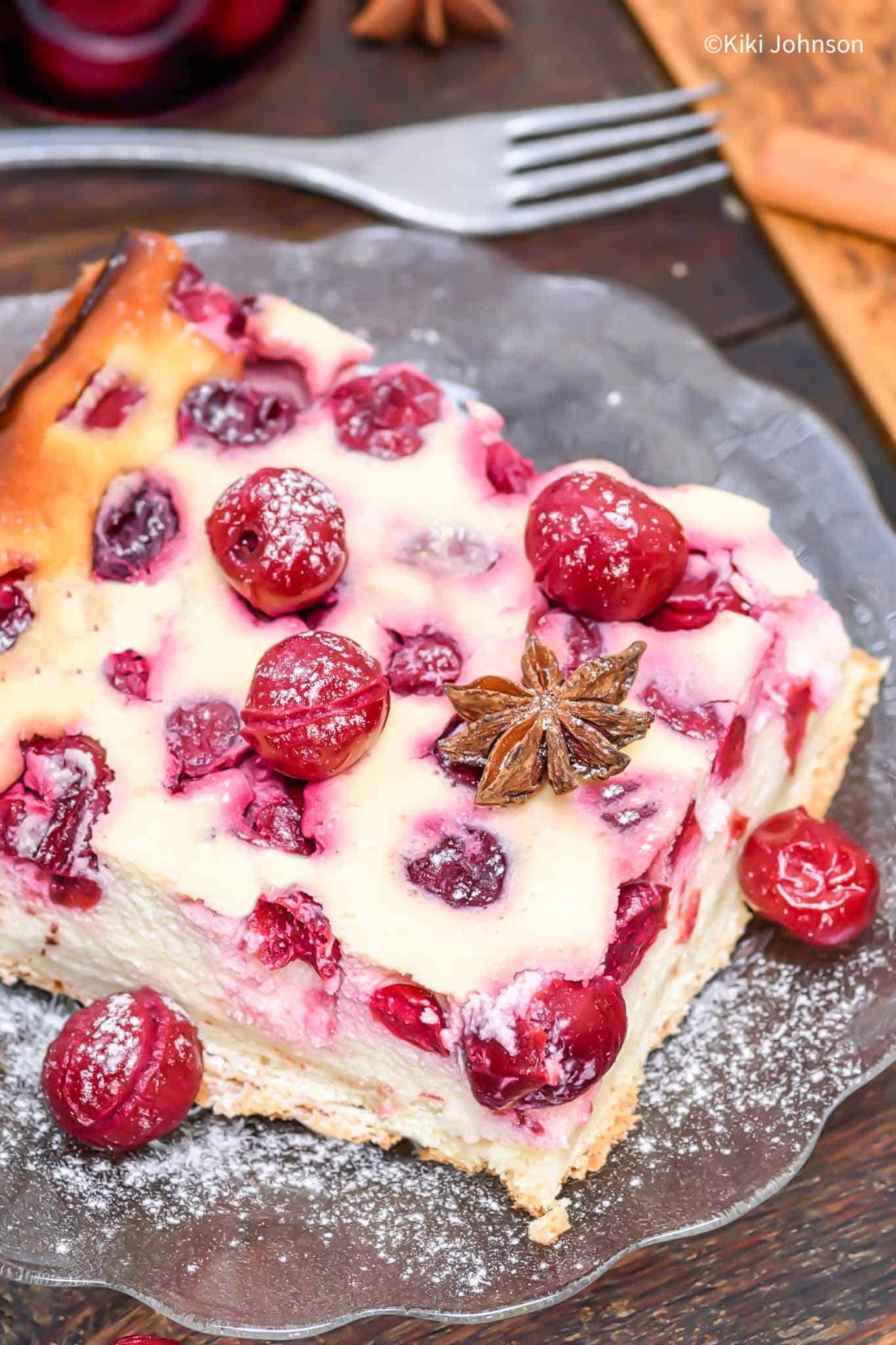 a slice of German sour cherry cheesecake on a cake plate with a fork on the side