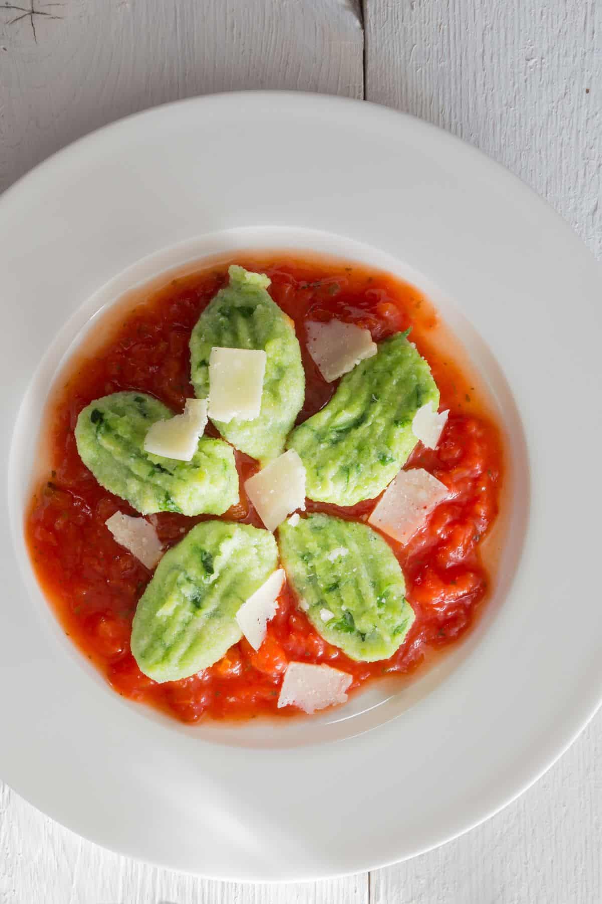 ein Teller mit Bärlauch Gnocchi auf Tomatensauce mit Parmesan besträut