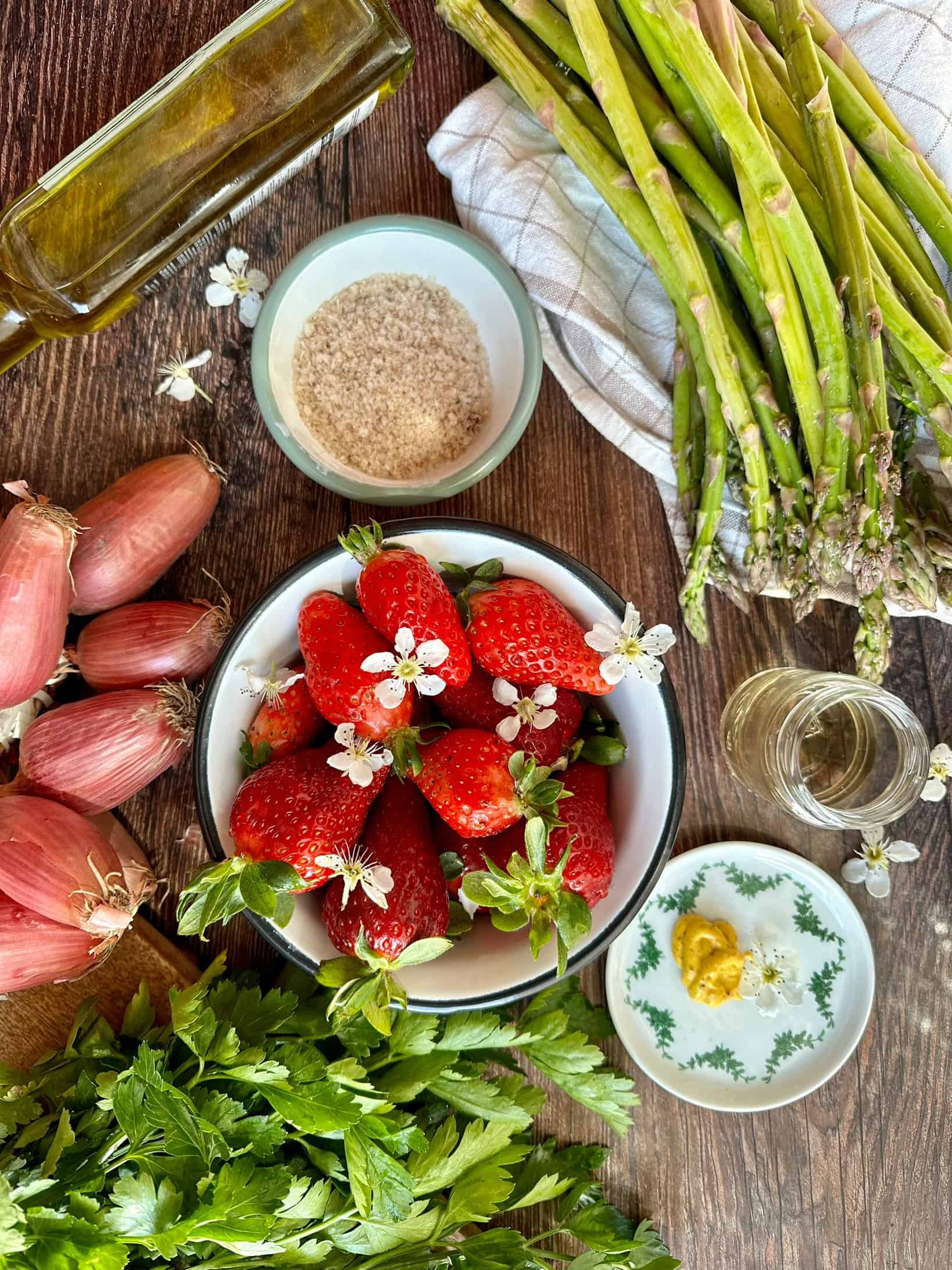 Zutaten für grünen Spargel-Salat mit Erdbeeren auf einem Holztisch. 