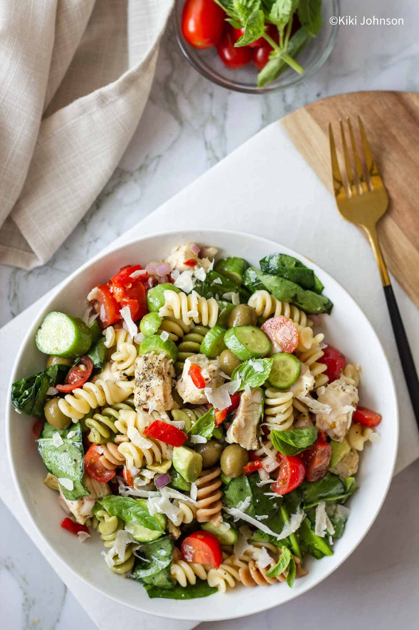 ein Teller mit mediterranem Pasta Salat mit Hähnchen und Gemüse in einem weißen Teller.