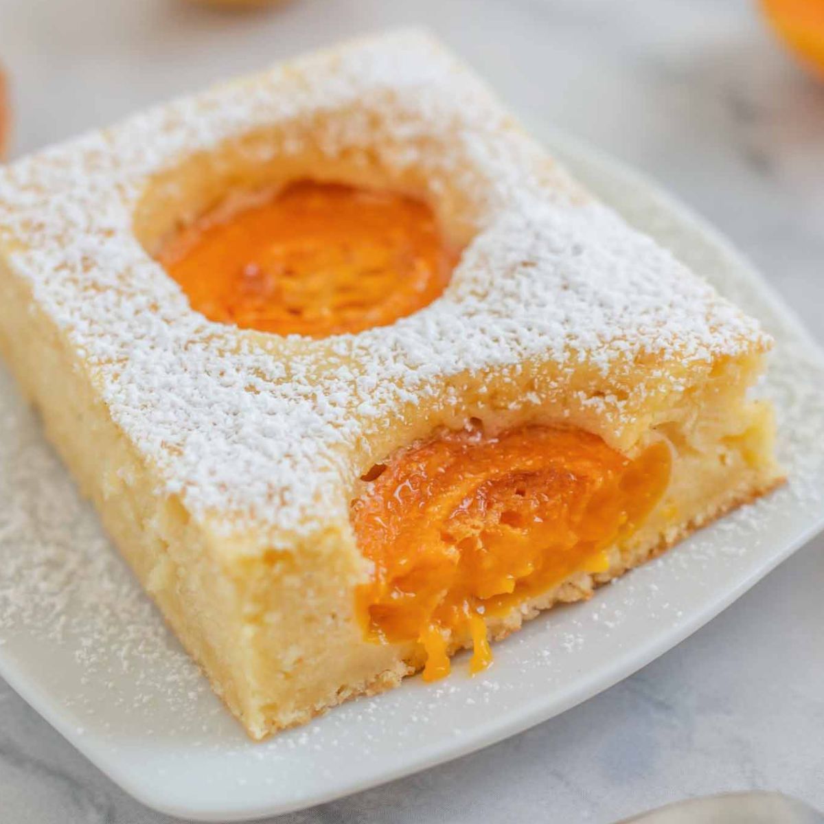 a slice of German fresh apricot sponge cake dusted with icing sugar.