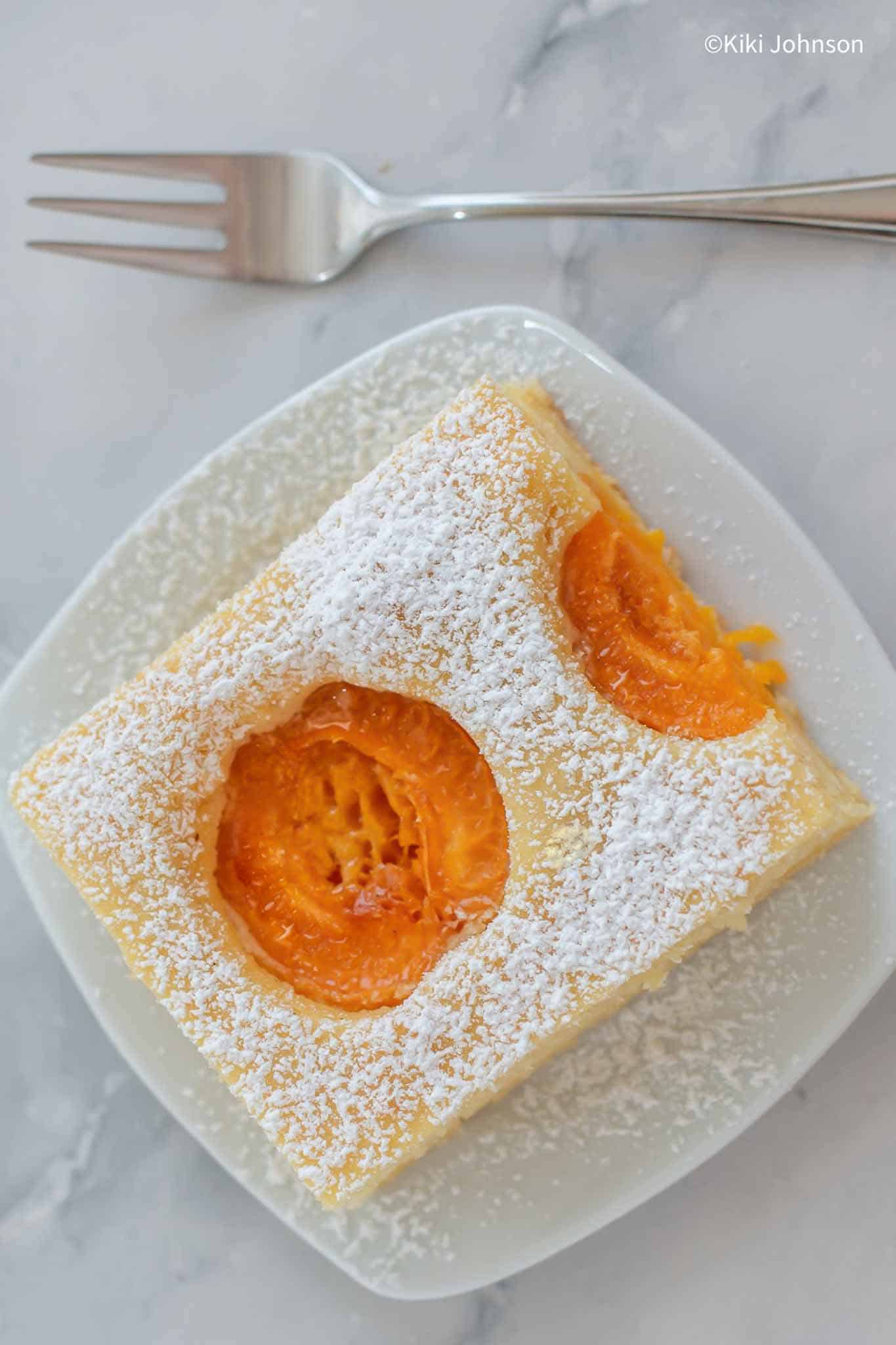 ein Stück Aprikosenkuchen mit frischen Aprikosen vom Blech.