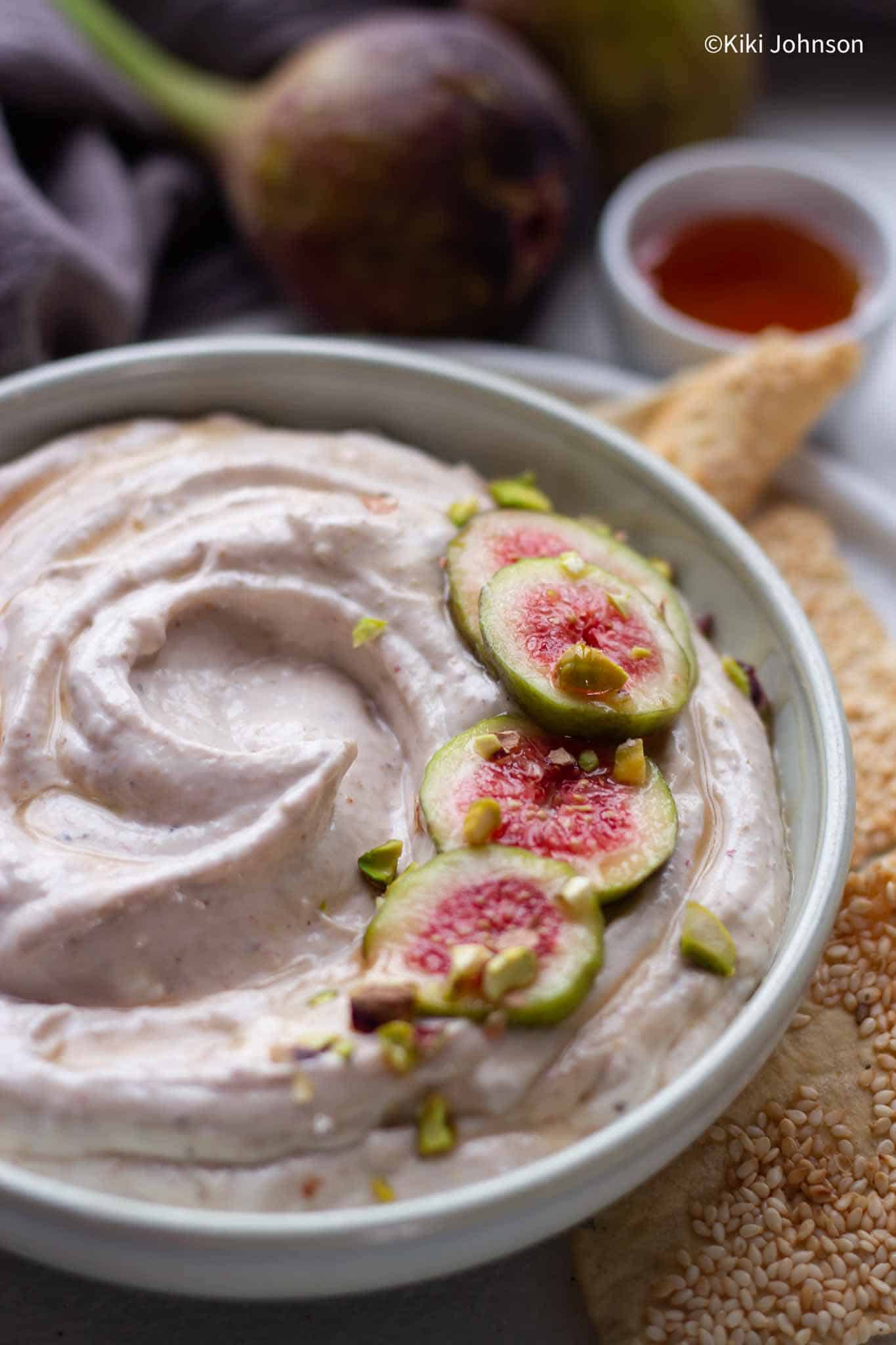 a bowl with fig spread decorated with fresh fig slices and pistachios.