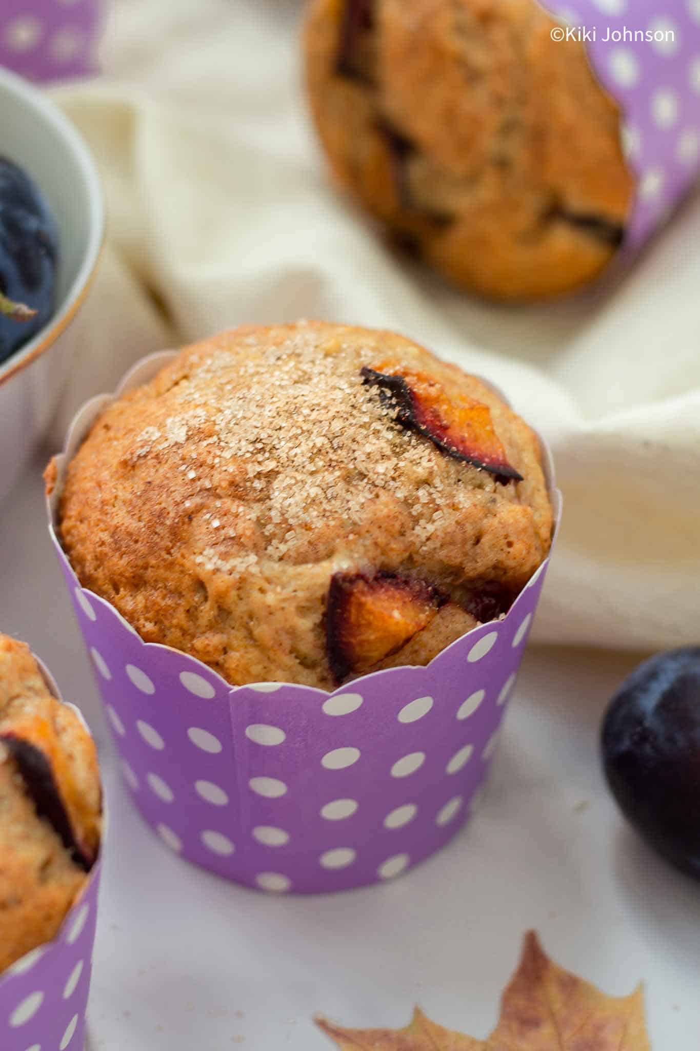 plum muffins with cinnamon sugar topping next to fresh italian plums.