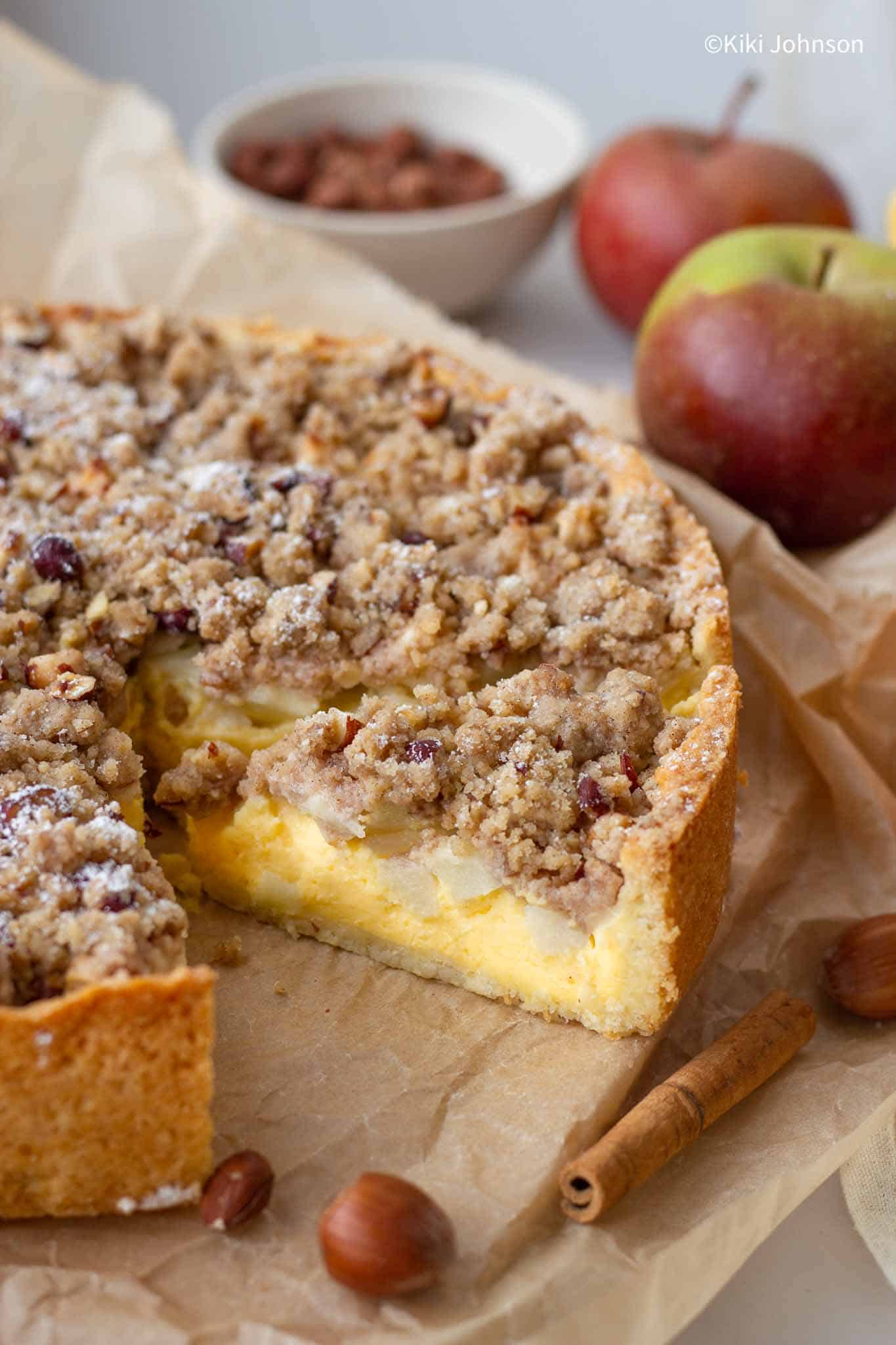 a sliced whole German apple cake with custard and topped with crumble topping.