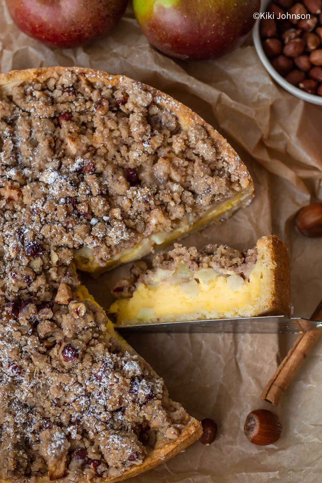 Traditional German Apple Cake with custard, apple chunks, and hazelnut crumble topping.