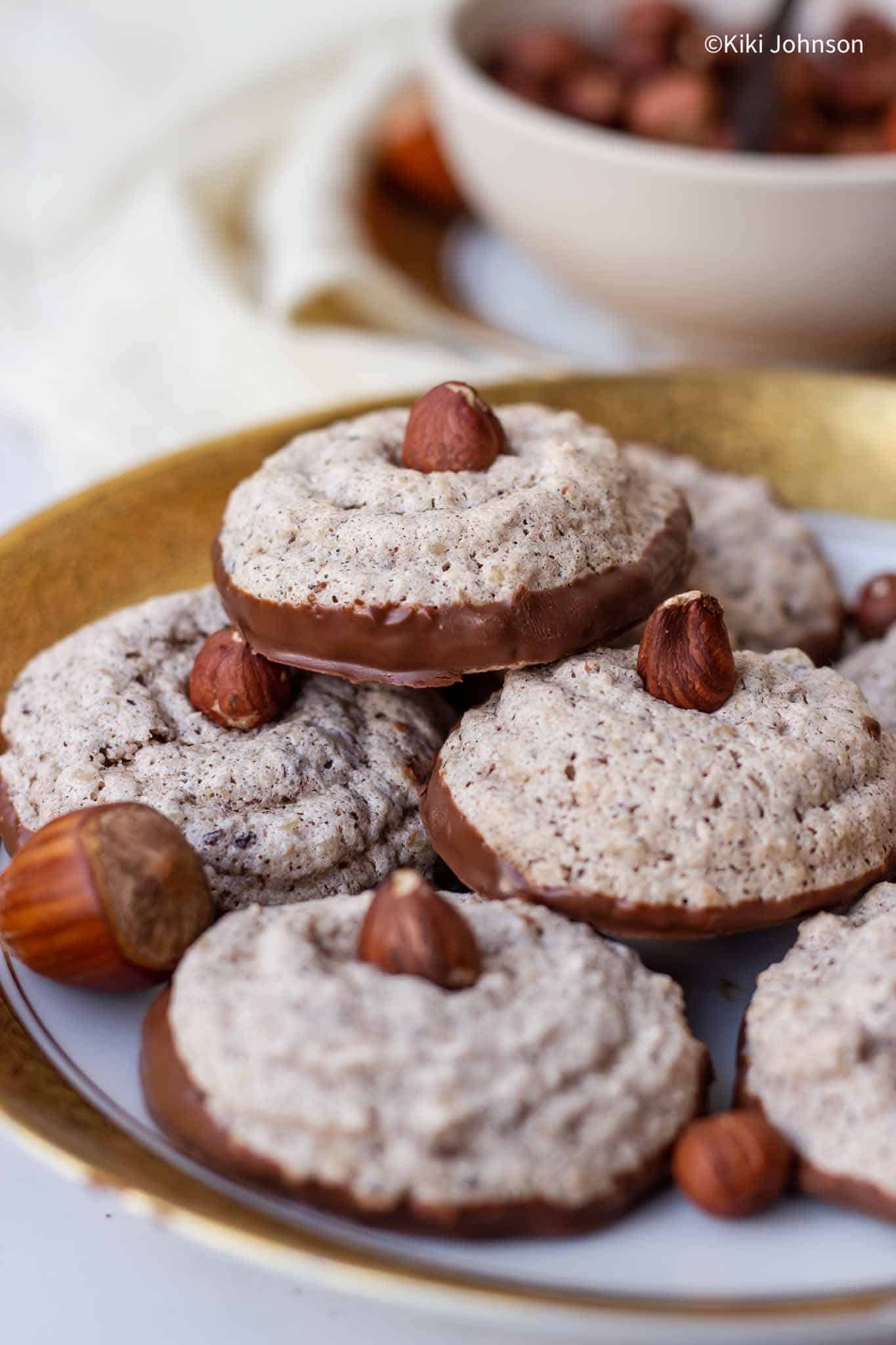 a plate with German hazelnut cookies topped with whole hazelnuts. 