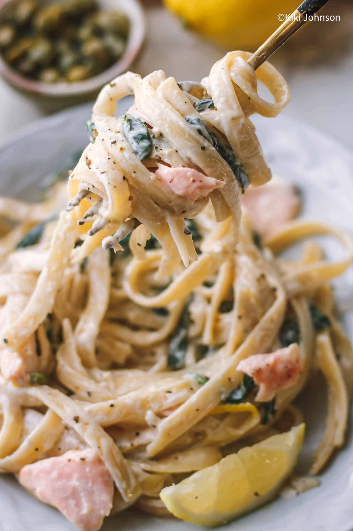 Ein Teller Pasta al Salmone mit Spinach und Zitronensauce mit einer goldenen Gabel 