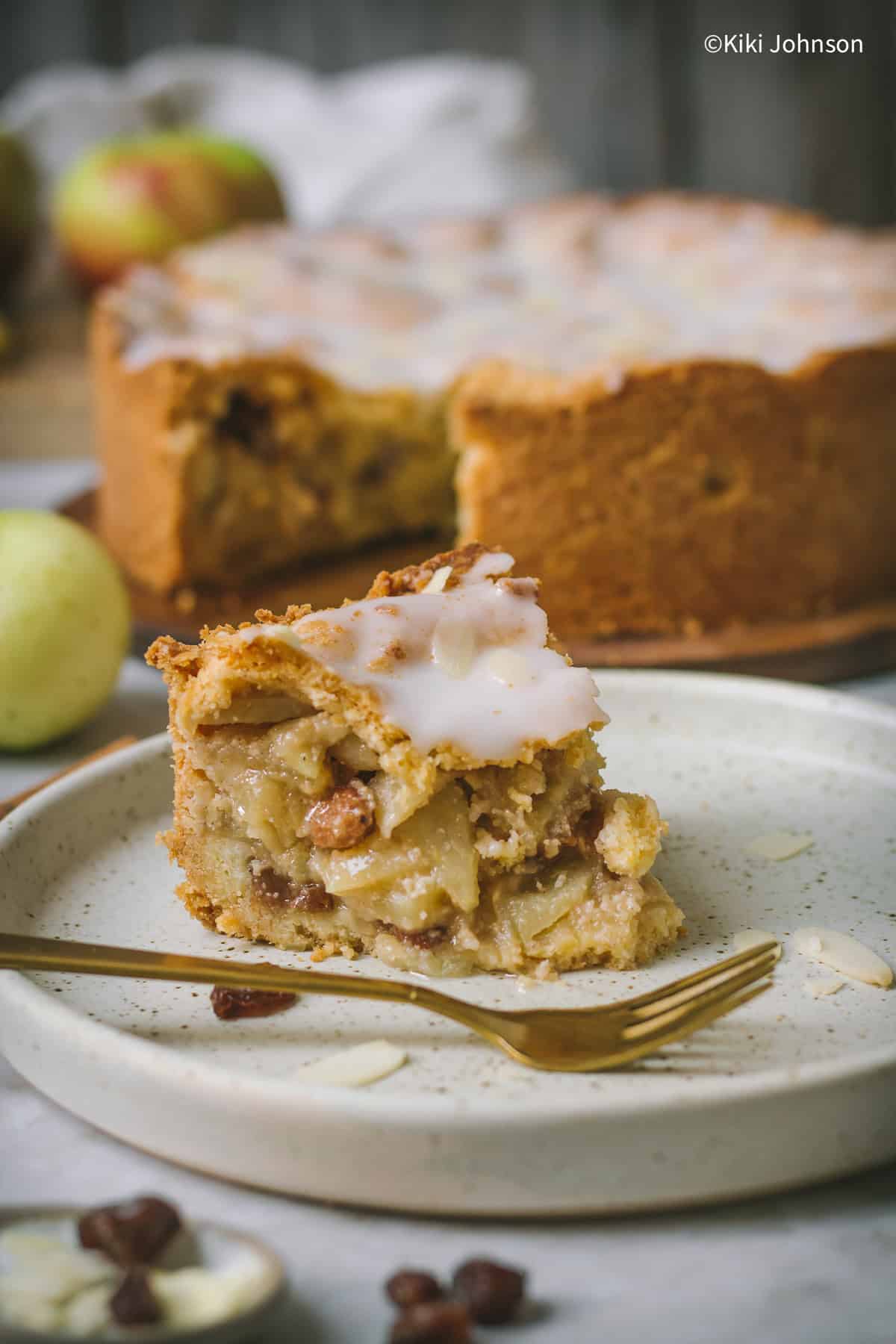 an half-eaten piece of German apple cake with lemon glaze and sliced almonds.