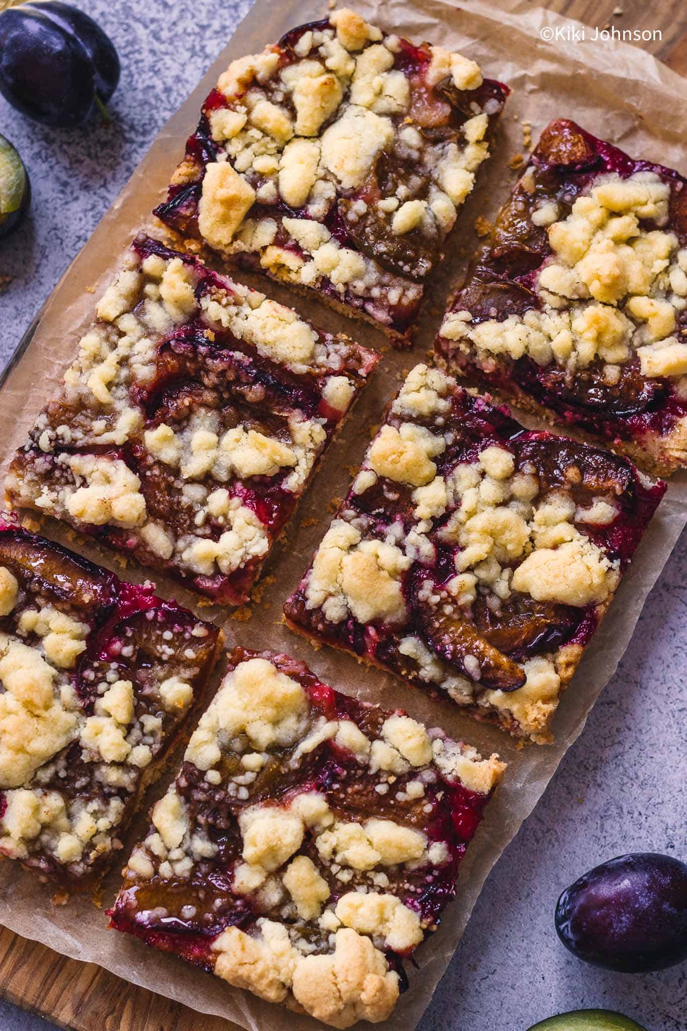 Ofenfrischer Zwetschgenkuchen mit Streusel und Mürbteig auf einem Holzbrett