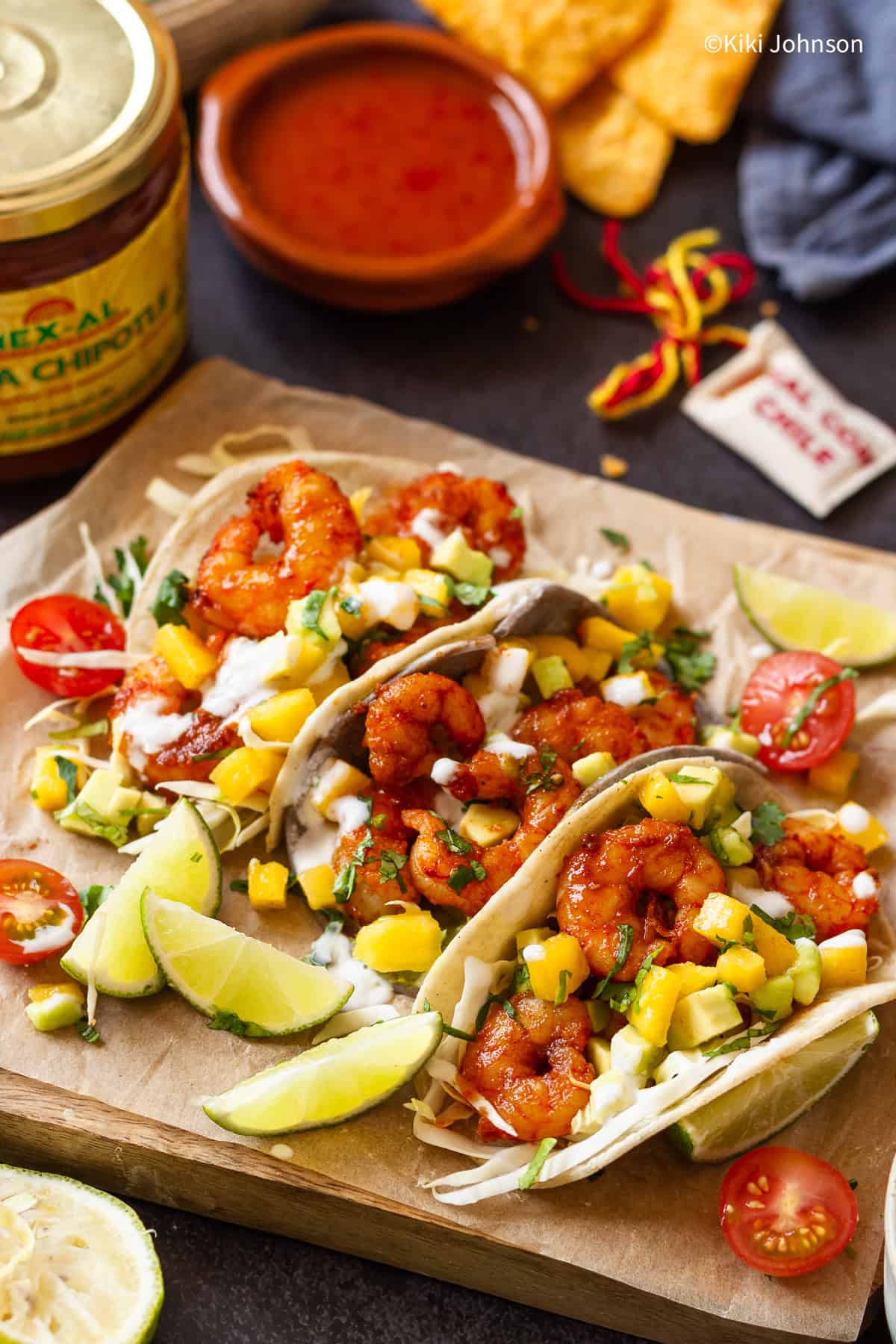 drei Garnelen Tacos mit Mango Avocado Salsa mit Limettenscheiben angerichtet und mit Chipotle Sauce serviert