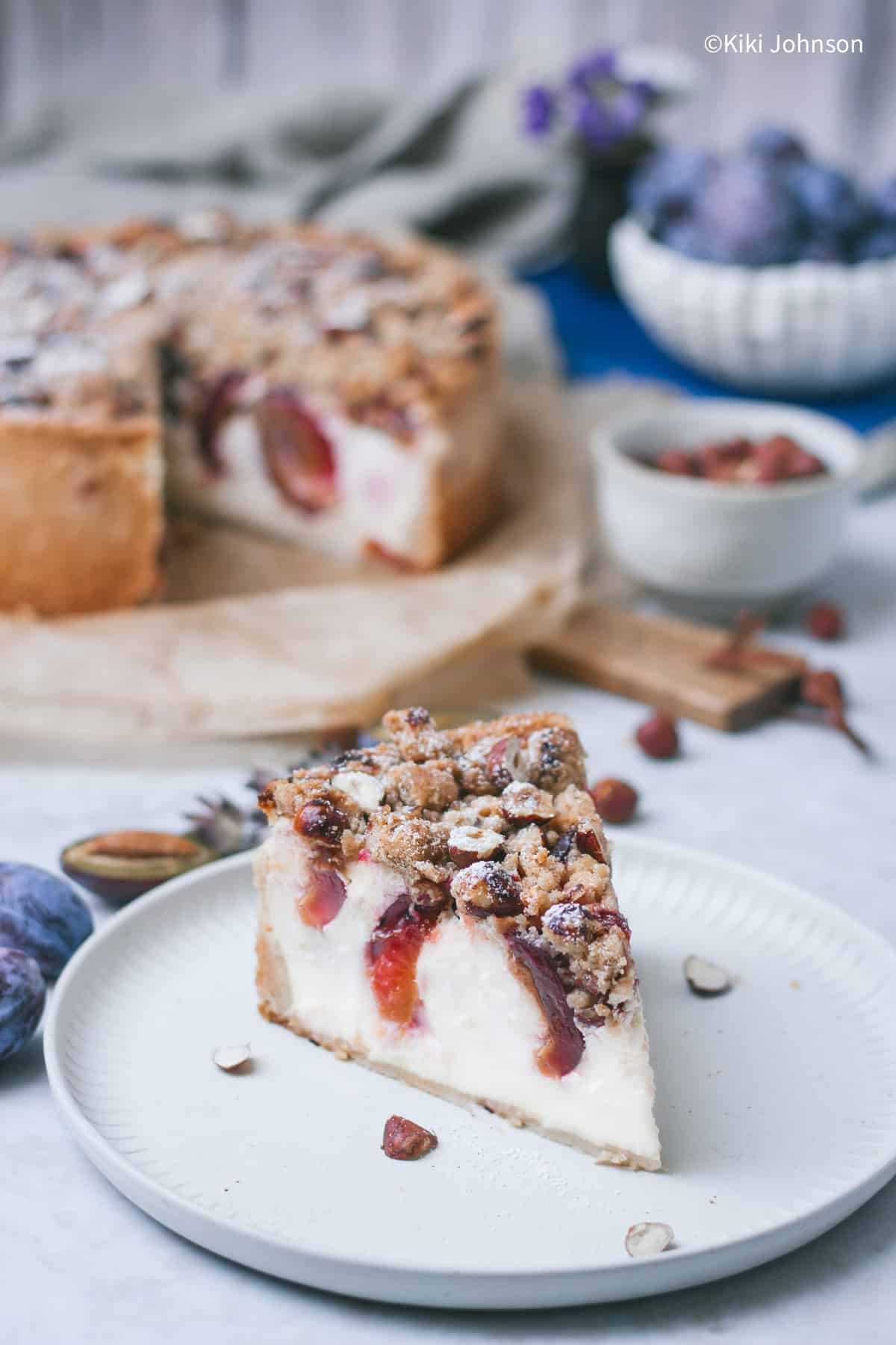 ein Stück Zwetschgen Käsekuchen mit Pflaumen und knusprigen Zimt Nussstreuseln.