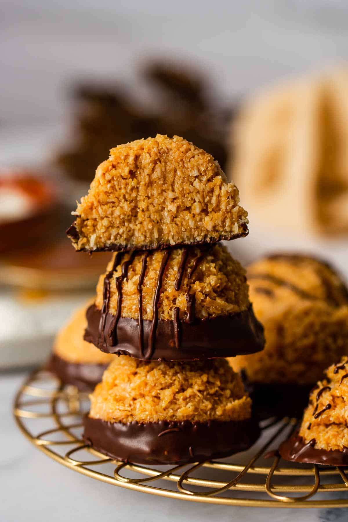 three stacked no bake coconut macaroons with dark chocolate on a cooling rack 