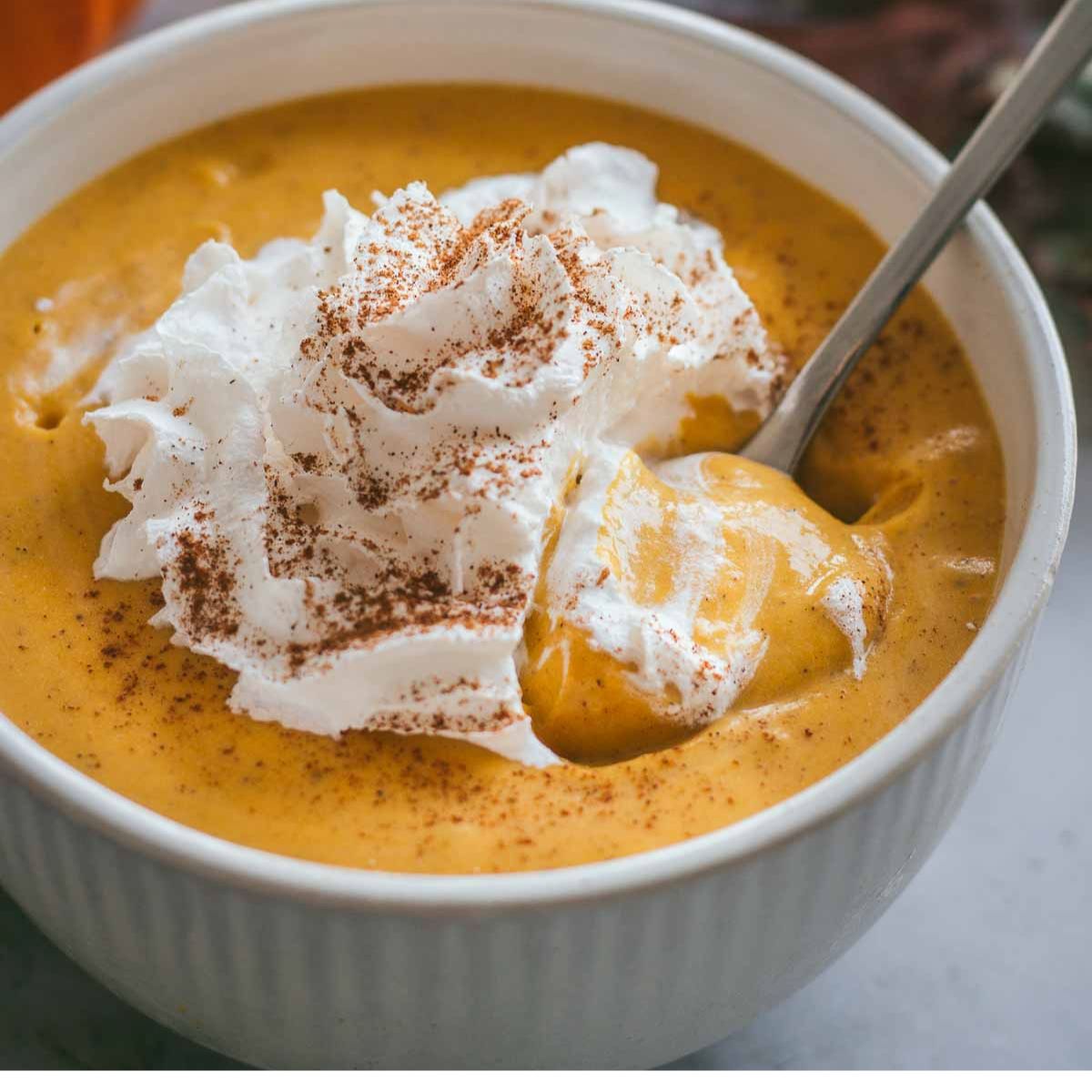 a bowl of vegan pumpkin mousse topped with coconut whip