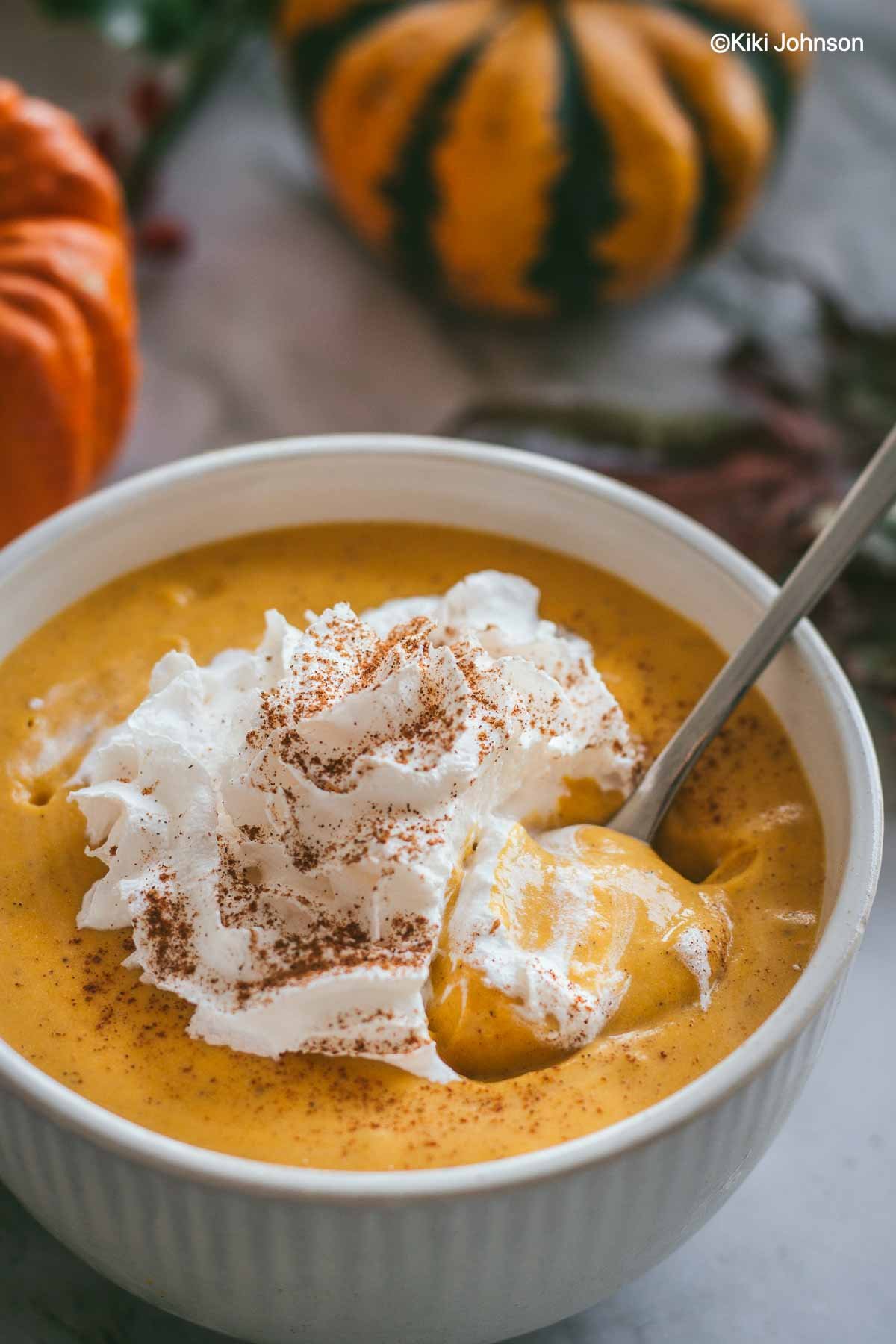 close-up of a bowl of vegan pumpkin mousse topped with coconut whipped cream and cinnamon