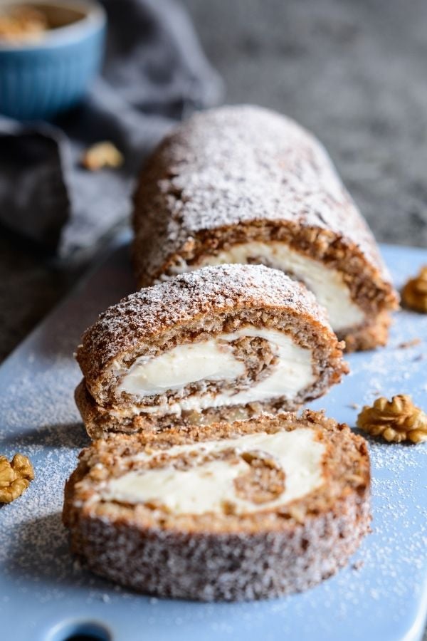 a sliced walnut coffee swiss roll dusted with icing sugar.