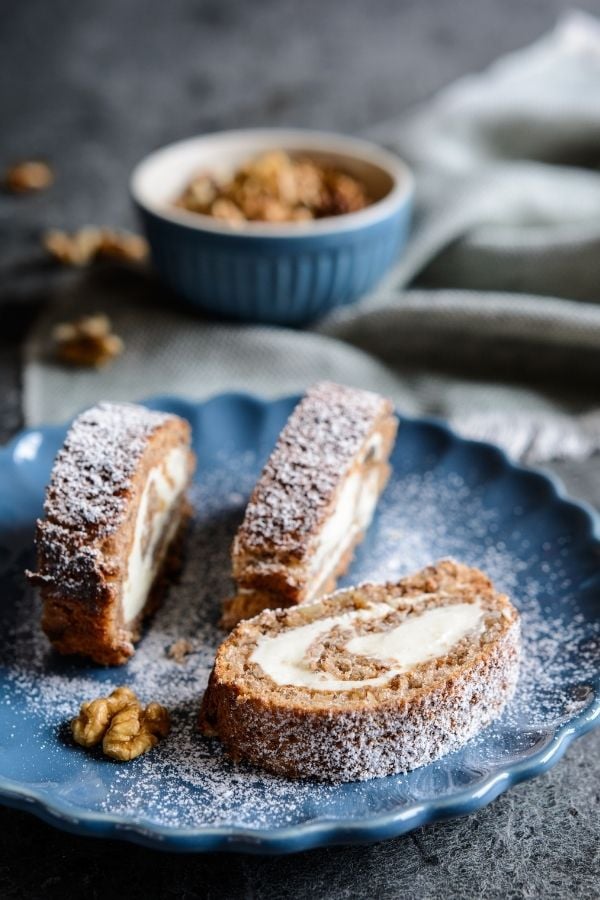 three slices of walnut coffee swiss roll on a blue plate.